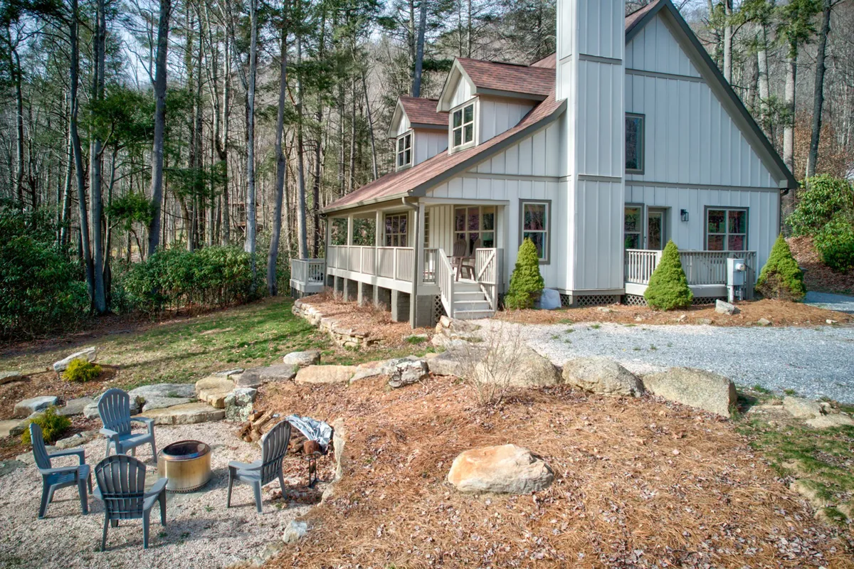 The photo spotlights a welcoming fire pit area near the house, ringed by nature and ample seating. The setting suggests opportunities for barbecues, s'mores, or quiet moments in the fresh air, with the house conveniently close for easy transitions between indoor and outdoor spaces.